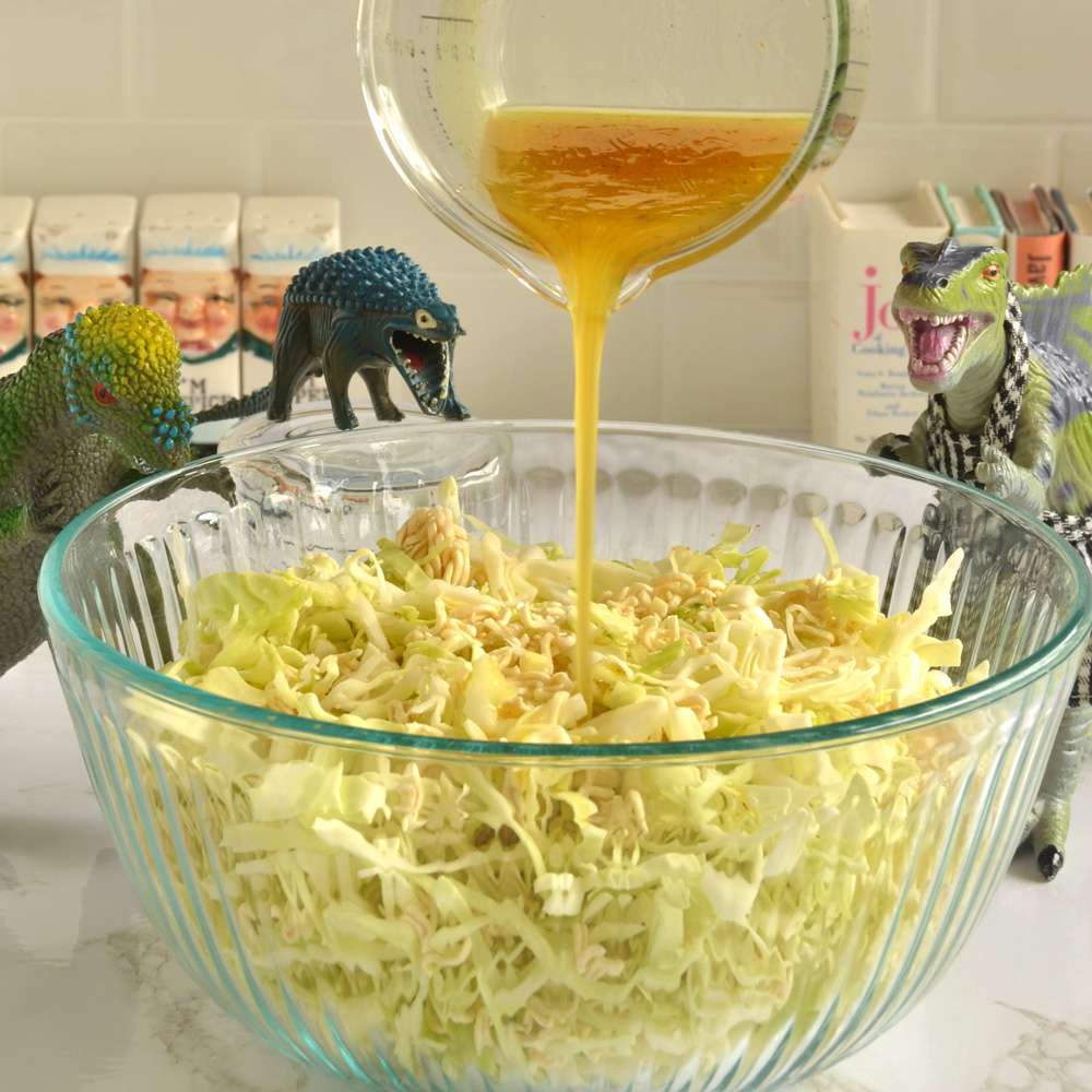 Vinaigrette being poured over the ramen coleslaw